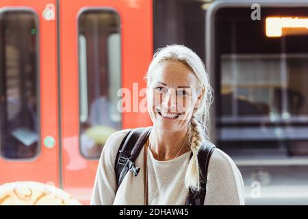 Portrait d'une femme mûre souriante avec sac à dos debout dans le train station Banque D'Images