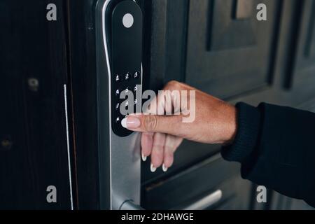 Main courte de femme déverrouillant le code de sécurité combiné sur la maison porte Banque D'Images