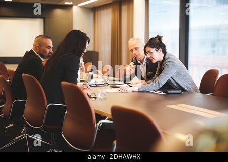 Les avocats masculins et féminins discutent du document à la table de conférence en réunion Banque D'Images