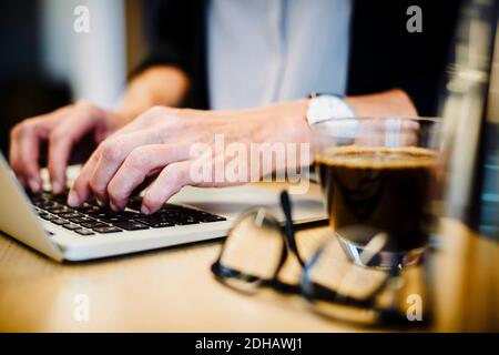 Section intermédiaire d'un avocat mature utilisant un ordinateur portable au bureau Banque D'Images