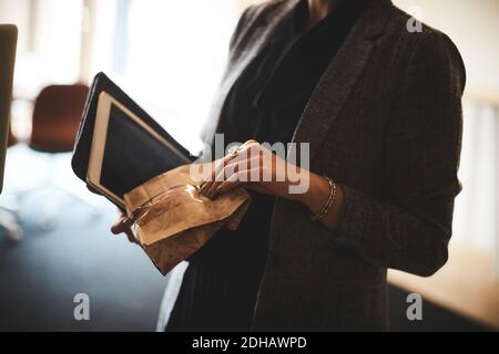 Mi-section de femme avocat tenant le paquet et la tablette numérique dans bureau Banque D'Images