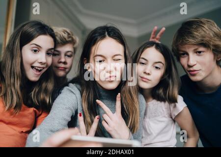 Des amis joyeux qui prennent le selfie à la maison grâce à leur téléphone portable Banque D'Images