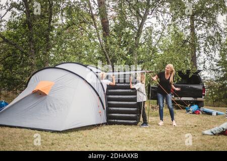 Mère parlant aux enfants portant un matelas dans une tente au camping site Banque D'Images