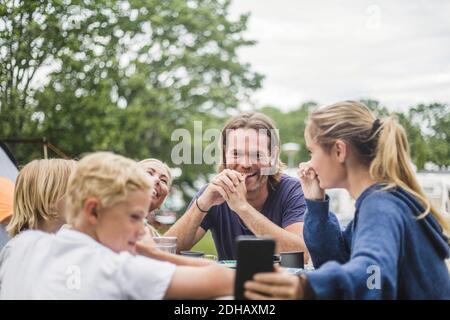 Adolescente prenant le selfie avec la famille sur la table au camping site Banque D'Images