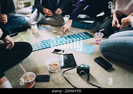 Petit groupe d'amis jouant à des jeux de société tout en prenant des collations sur le sol à la maison Banque D'Images