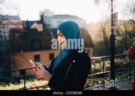 Jeune femme musulmane portant le hijab à l'aide d'un smartphone en ville Banque D'Images