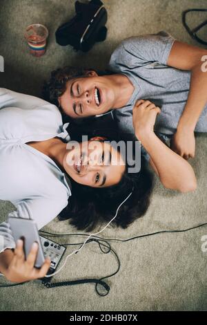 Directement au-dessus de la photo de vos amis heureux écoutant de la musique ensemble couché sur la moquette à la maison Banque D'Images