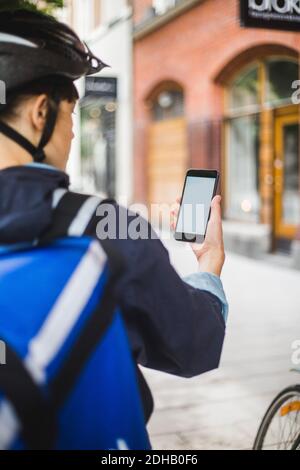 Image rognée de la femme livree de nourriture en utilisant la carte sur SMART téléphone en ville Banque D'Images