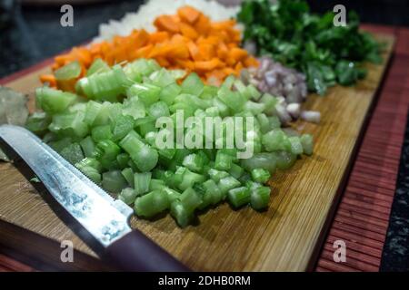 Légumes mélangés avec brunoise coupé pour faire sauter sur une planche à découper en bois (carottes, céleri, oignons et échalotes) Banque D'Images