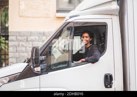 Portrait d'une femme souriante qui conduit un camion Banque D'Images