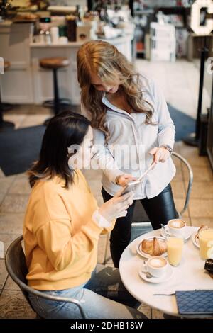 Photographes féminins multi-ethniques partageant un smartphone dans un café Banque D'Images