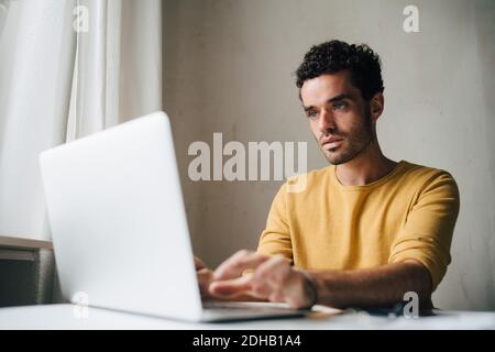 Mid adult man using laptop at home Banque D'Images