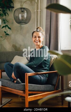 Portrait d'une femme de taille moyenne souriante assise sur un fauteuil accueil Banque D'Images