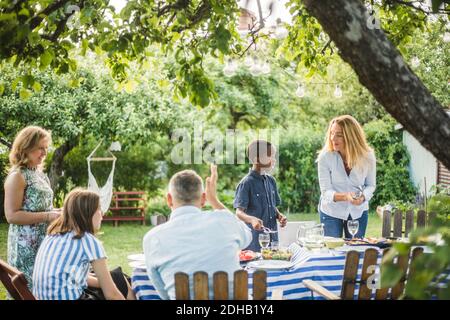 Garçon aidant la femme à organiser la table par la famille à l'arrière-cour Banque D'Images