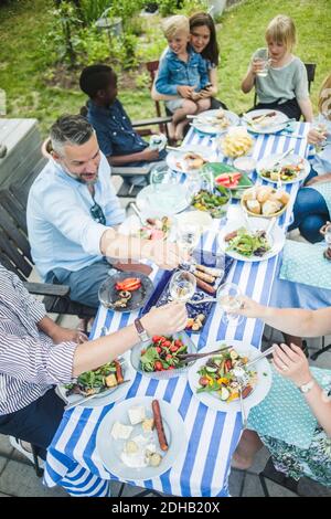 Des amis et de la famille toaster des lunettes de vin tout en déjeunant dans le jardin fête Banque D'Images