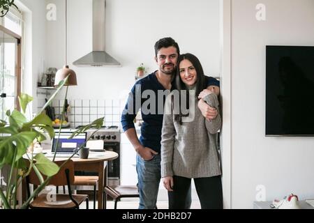 Portrait d'un couple souriant debout au mur à la maison Banque D'Images