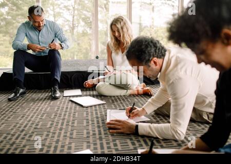 Hommes et femmes professionnels des affaires écrivant sur des papiers en convention centre Banque D'Images