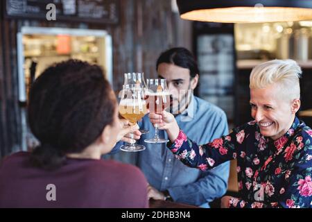 Des amis multiethniques toastent des lunettes tout en étant assis au bar Banque D'Images