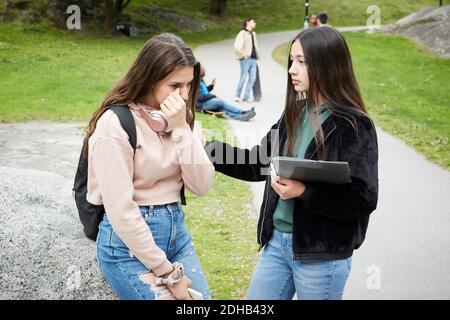 Une adolescente regarde une amie pleurer tout en étant assise rock au parc Banque D'Images