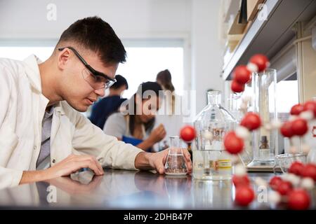 Jeune homme confiant étudiant en chimie par des amis en laboratoire à université Banque D'Images