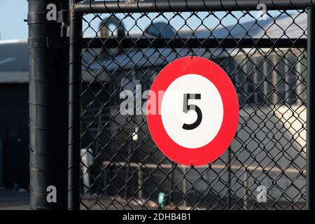 Vue du panneau de signalisation circulaire blanc avec bordure rouge indiquant la limite de vitesse de 5 km/h, sur une clôture en treillis métallique Banque D'Images