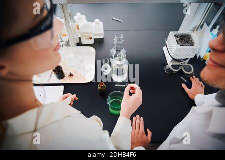Vue en grand angle des jeunes étudiants multiethniques debout avec du liquide solutions au laboratoire de chimie Banque D'Images