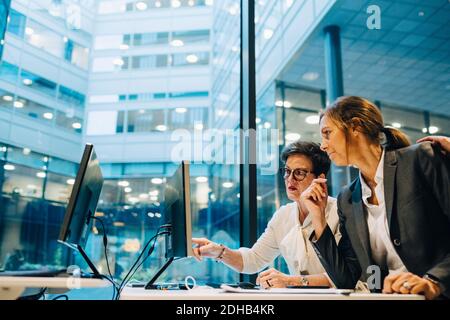 Les femmes d'affaires discutent en regardant l'ordinateur pendant qu'elles travaillent au bureau Banque D'Images