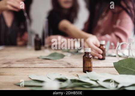 Mi-section de collègues femmes préparant le parfum à la table dans l'atelier Banque D'Images