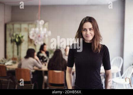 Portrait d'une femme confiante propriétaire de brunette debout contre ses collègues atelier Banque D'Images