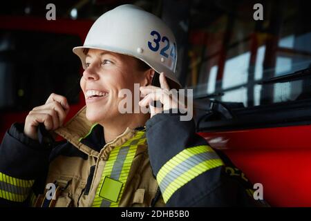 Pompier souriant portant un casque à la caserne de pompiers Banque D'Images