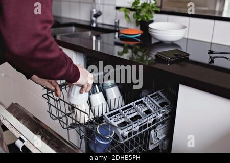 Les mains de l'homme âgé qui s'occupe de la tasse au lave-vaisselle sont coupées à accueil Banque D'Images