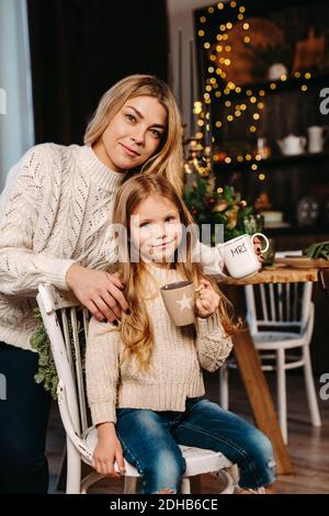 Bonne petite fille et sa mère mangeant des biscuits avec du lait à la maison Banque D'Images