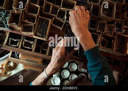 Directement au-dessus de la vue de la femme senior vendeur enlever les ongles de la boîte en carton dans le magasin de quincaillerie Banque D'Images