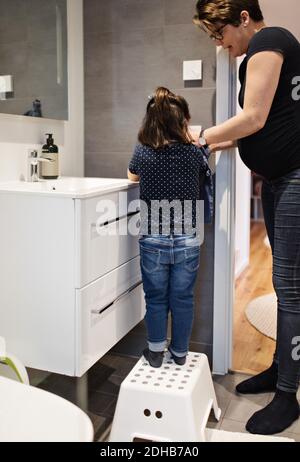 Mère aidant la fille à se laver les mains à la maison Banque D'Images