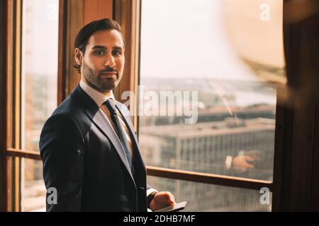 Portrait d'un conseiller homme confiant debout par fenêtre au service juridique bureau Banque D'Images