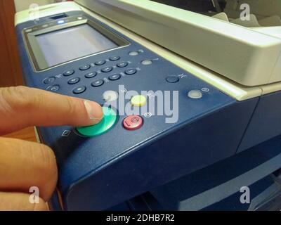 Homme d'affaires appuyer à la main sur le bouton sur le panneau de l'imprimante, imprimante scanner laser bureau photocopieur fournitures concept de démarrage. Banque D'Images