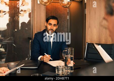 Portrait d'un avocat de milieu d'adulte confiant avec des documents à la conférence table dans le bureau d'avocats Banque D'Images