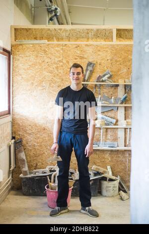 Portrait complet d'un jeune homme plein de confiance stagiaire debout avec équipement en atelier Banque D'Images