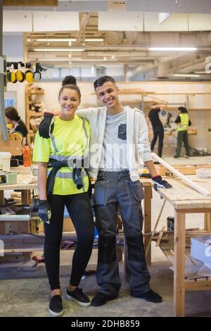 Portrait complet d'une femme stagiaire souriante debout avec le bras autour d'un collègue de travail Banque D'Images