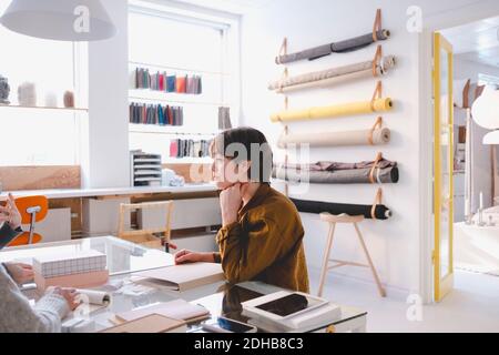 Jeune couturier en discussion avec des collègues en atelier Banque D'Images
