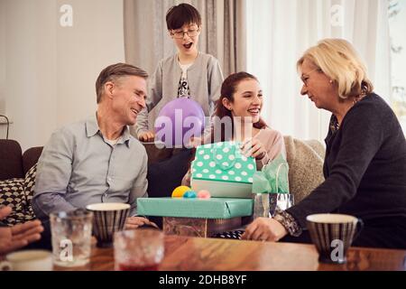 Garçon regardant la sœur heureuse recevant des cadeaux de grands-parents à accueil Banque D'Images