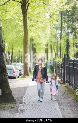 Pleine longueur de mère et de fille tenant les mains pendant la marche sur le sentier Banque D'Images