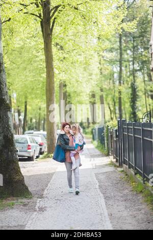 Pleine longueur de la mère transportant sa fille tout en marchant sur le sentier Banque D'Images