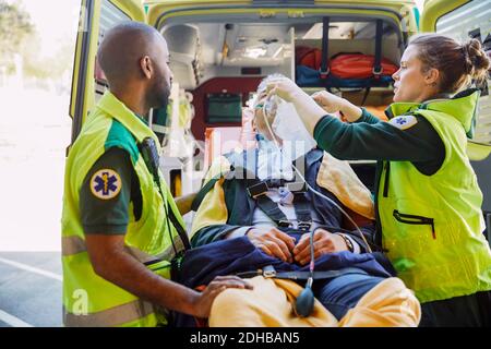 Hommes et femmes ambulanciers paramédicaux qui traitent l'homme d'affaires avec une RCP à l'extérieur de l'ambulance Banque D'Images