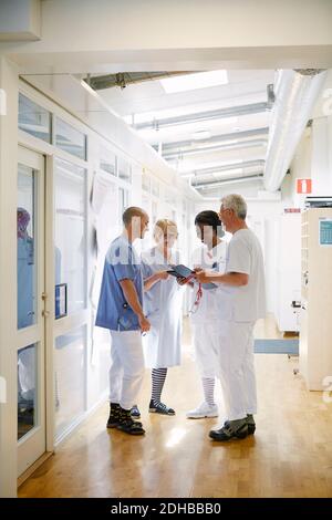 Toute la longueur des professionnels de la santé discutant sur tablette numérique pendant debout dans le couloir de l'hôpital Banque D'Images
