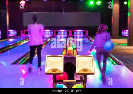 Des moniteurs informatiques contre les adolescentes qui lancent des balles sur le parquet au bowling Banque D'Images