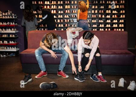 Adolescent aidant un ami à porter des chaussures tout en étant assis sur un canapé au bowling Banque D'Images