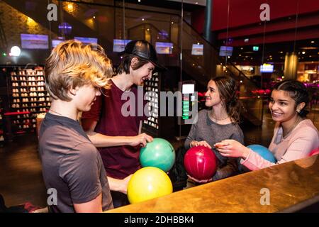 Des amis adolescents multiethniques et gais debout avec des boules de bowling Banque D'Images