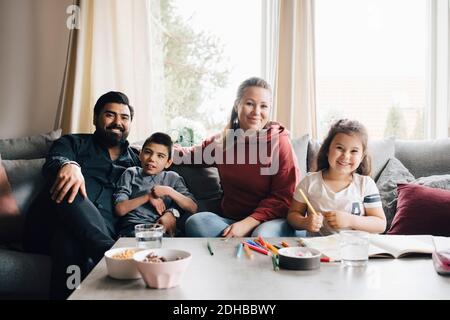 Portrait de famille souriante assis sur le canapé contre la fenêtre à accueil Banque D'Images