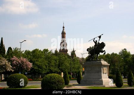 Statue de bronze sur une plinthe en pierre d'El CID on Equitation avec des buissons topiaires et une tour de la place d'Espagne Dans le soleil de l'après-midi Séville Andalousie Espagne Banque D'Images